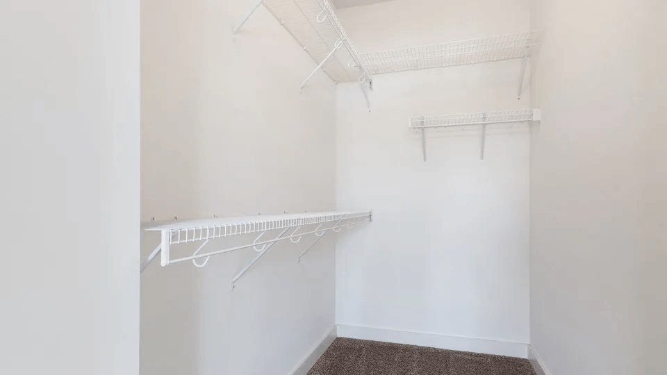 A white closet with two racks of clothes.