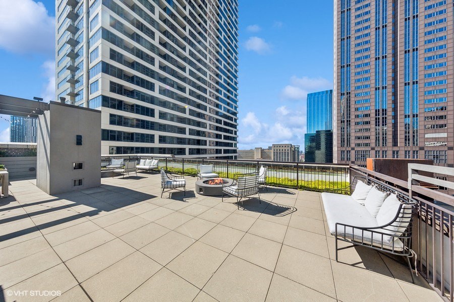 a rooftop terrace with a view of skyscrapers and a bench
