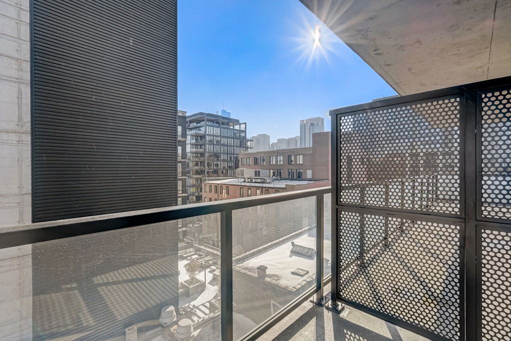 A balcony with a metal railing overlooks a cityscape.
