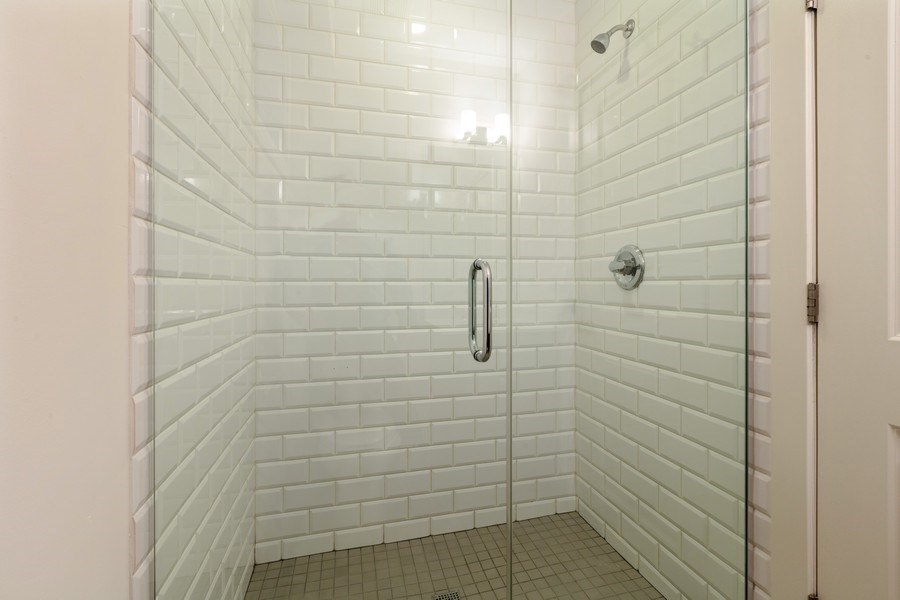 A white tiled shower with a glass door.
