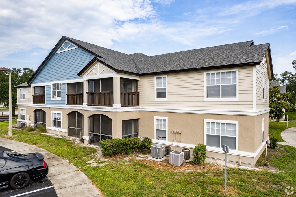 A two-story apartment building with a blue roof and beige walls.