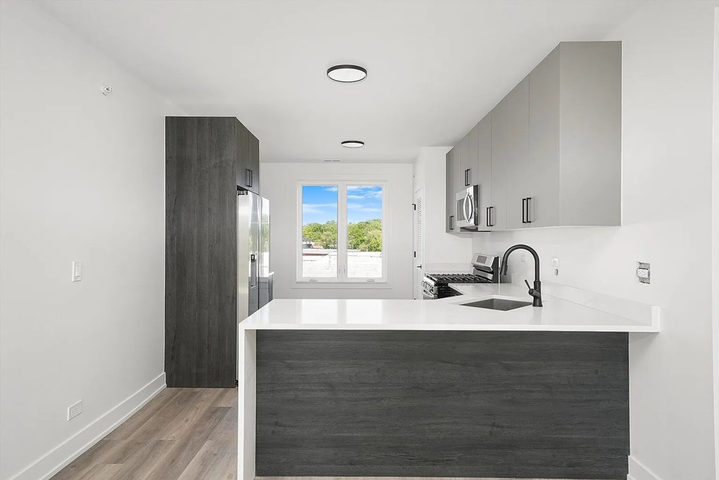 A modern kitchen with a large island and a view of the outdoors.