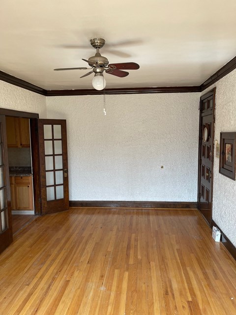 an empty living room with a ceiling fan and wood floors