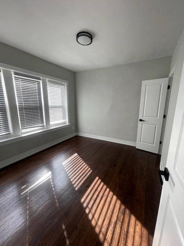 an empty living room with wood floors and a window