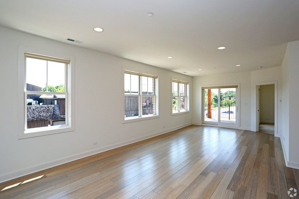 A large empty room with wooden floors and windows.
