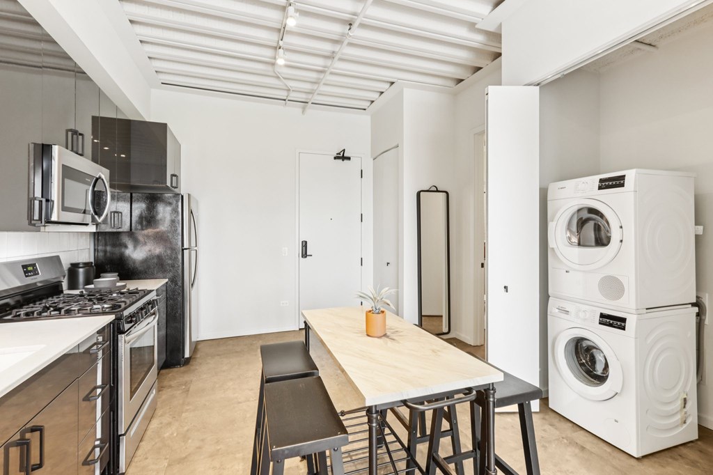 A modern kitchen with a wooden table and stainless steel appliances.