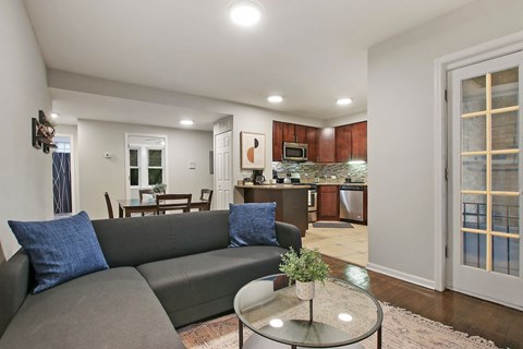 A living room with a grey couch and a glass table.