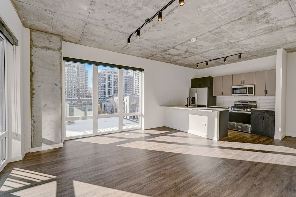 A spacious kitchen and living room with wooden floors and a view of the city.