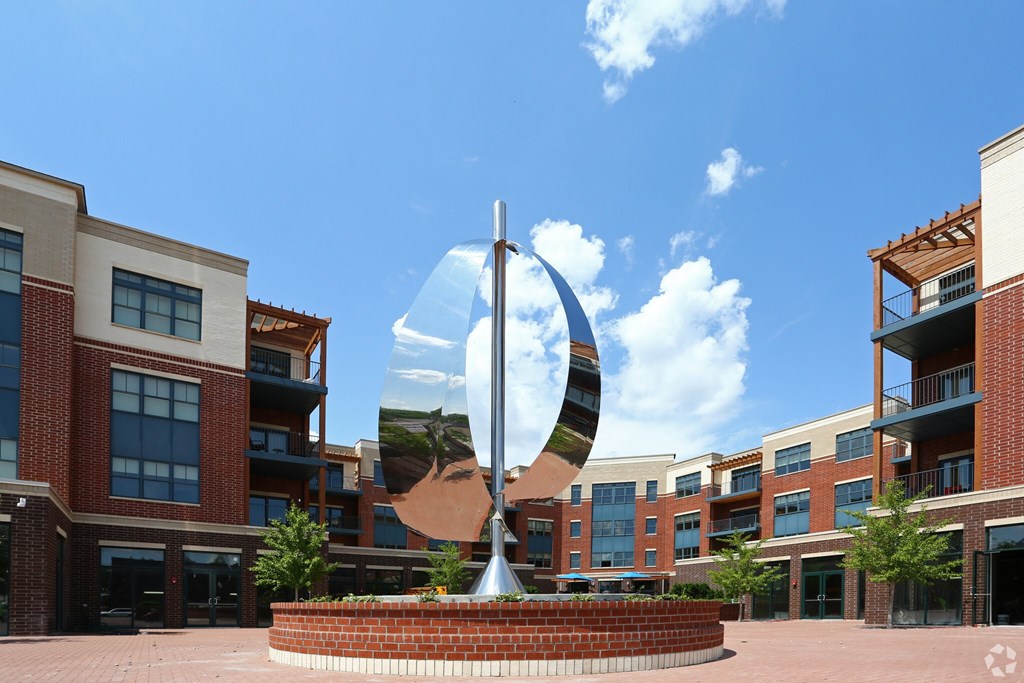 A large sculpture in the middle of a courtyard surrounded by buildings.