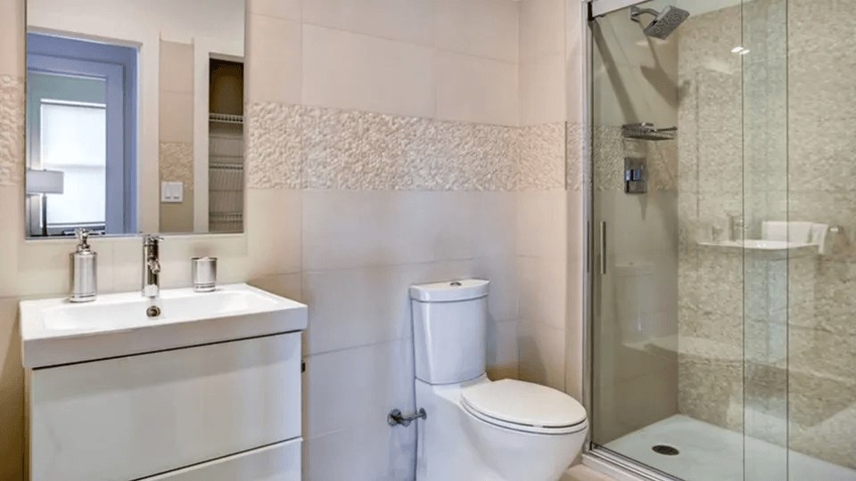 A white bathroom with a toilet, sink, and shower.