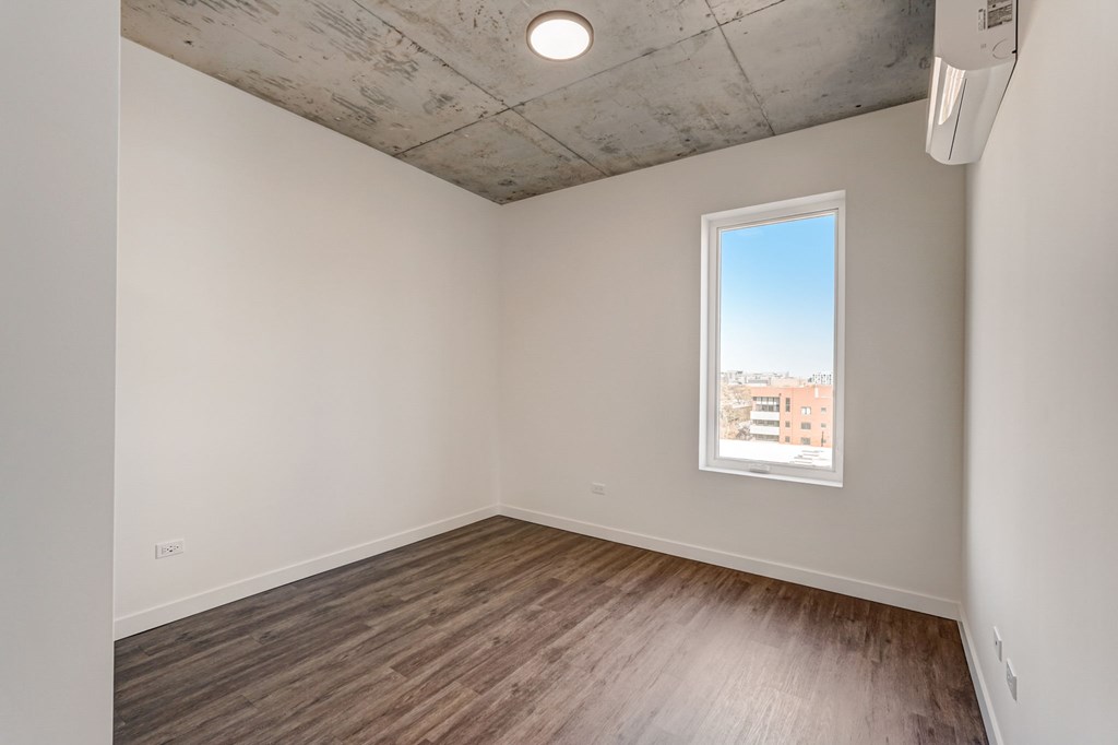 Empty room with a window and wooden floor.