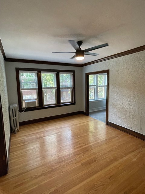an empty living room with wood floors and a ceiling fan