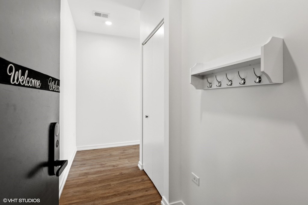 A hallway with a wall-mounted coat rack and a "Welcome" sign on the wall.