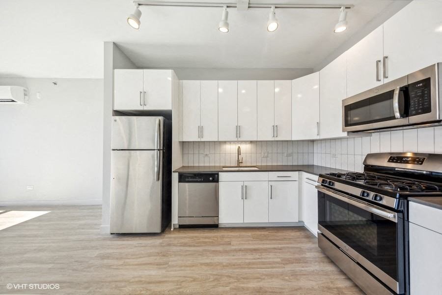 a white kitchen with stainless steel appliances and white cabinets