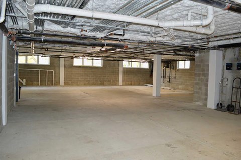 A spacious basement with concrete floors and exposed pipes.