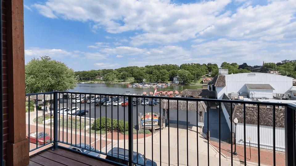 A balcony overlooks a parking lot and a green landscape.