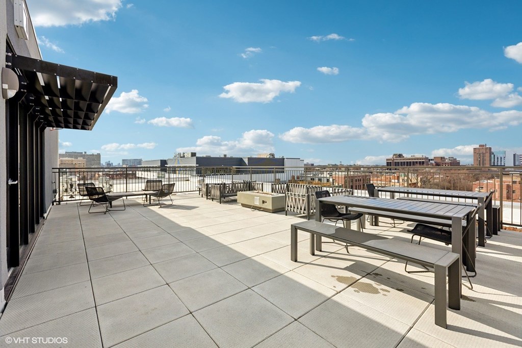 A rooftop patio with a bench and a table.
