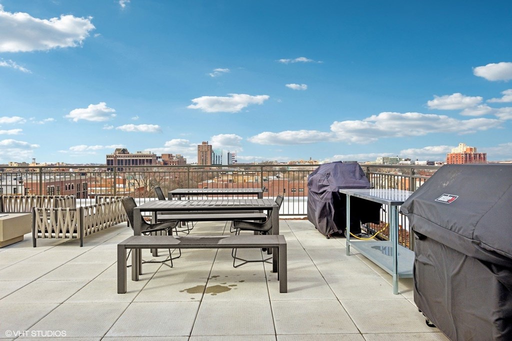 A rooftop patio with a table and chairs overlooking a city skyline.