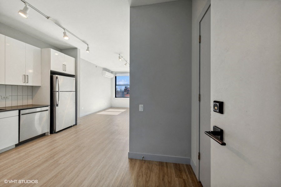 an empty kitchen and living room with a refrigerator and