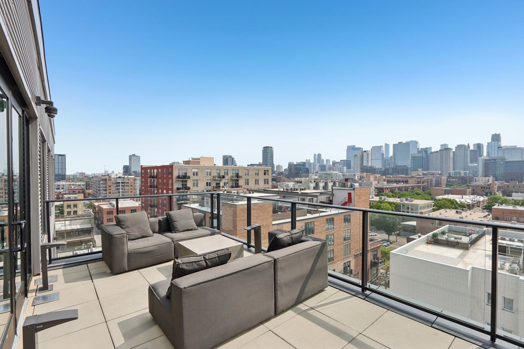 A balcony with a couch and a table overlooking a city skyline.