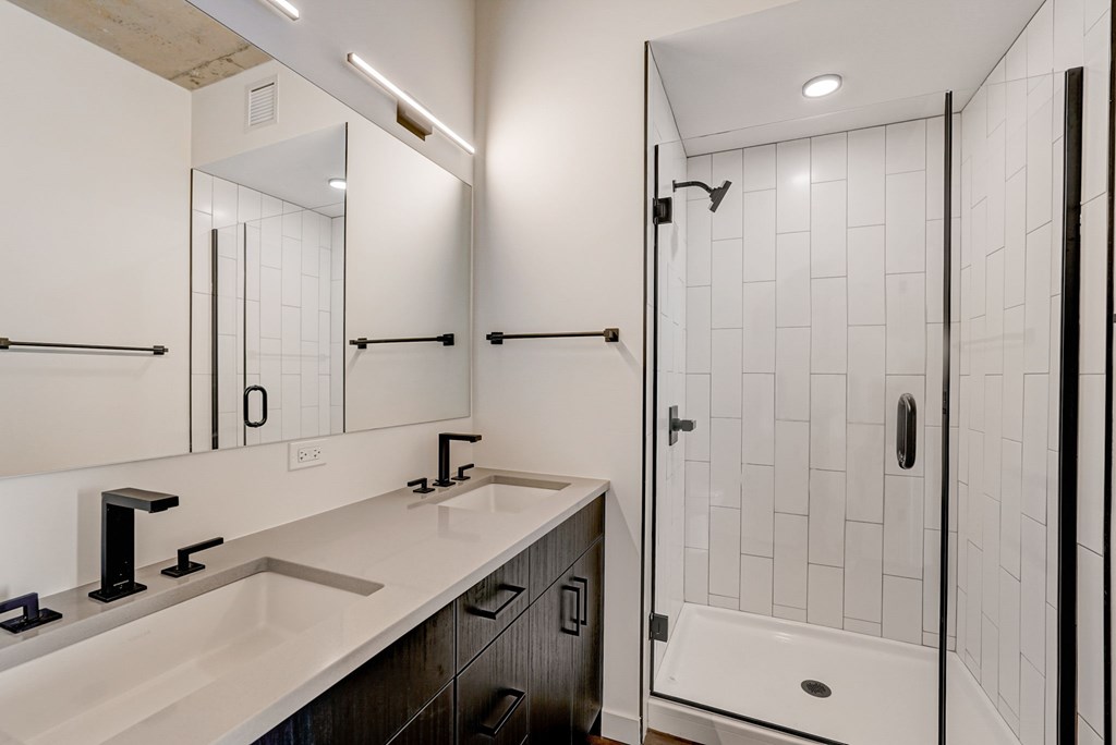 A white bathroom with a sink and a shower.