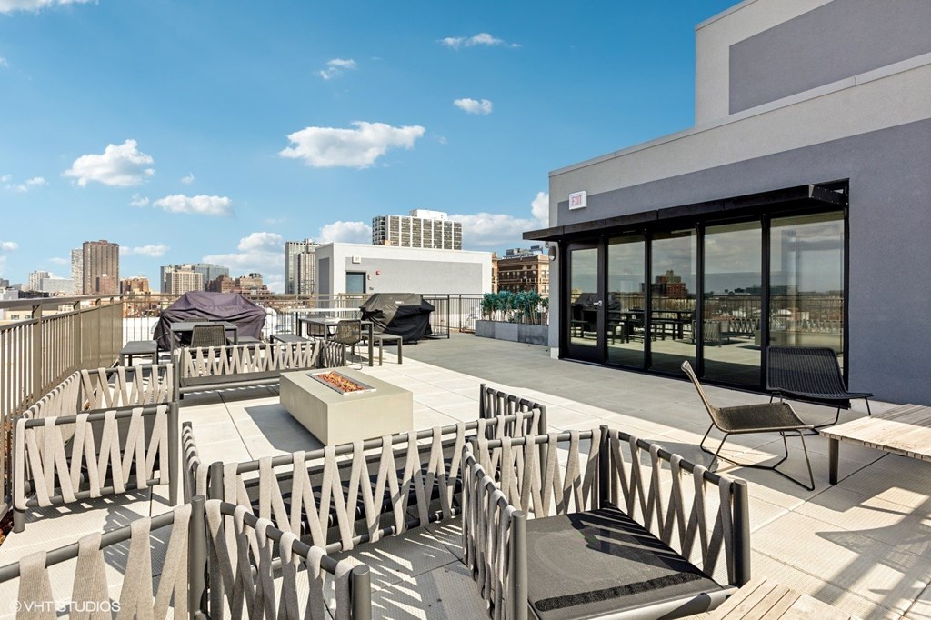 A rooftop patio with a table and chairs overlooking a city skyline.