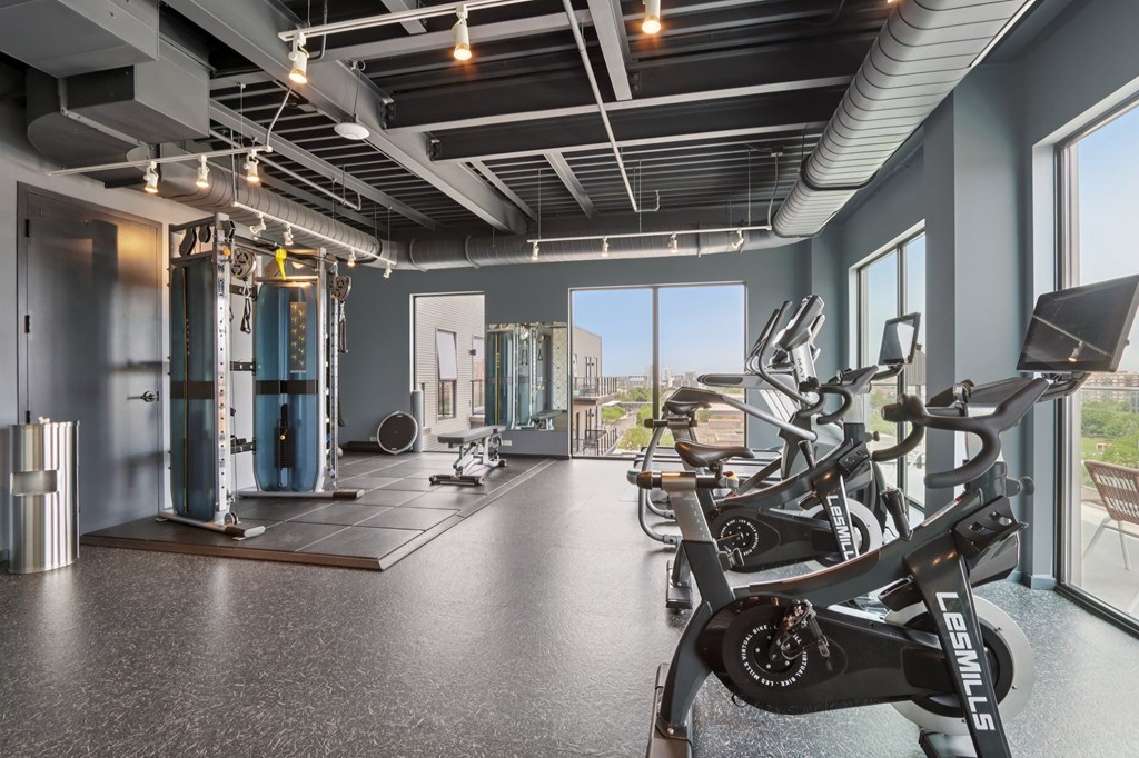 A gym with a row of stationary bikes and a row of treadmills.