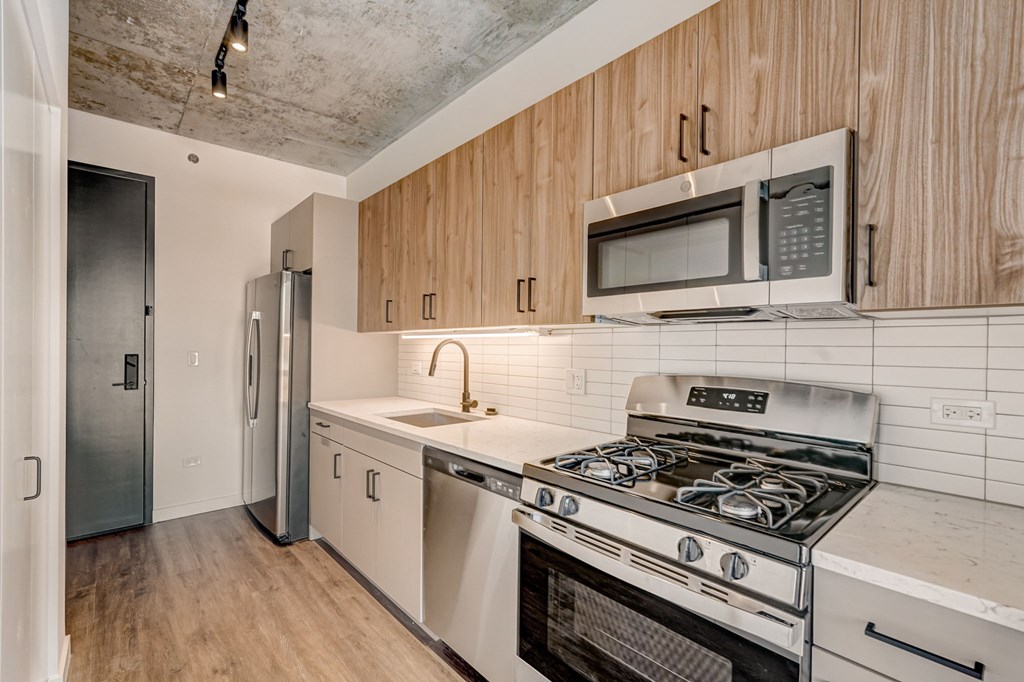 A kitchen with a stove, refrigerator, and microwave.