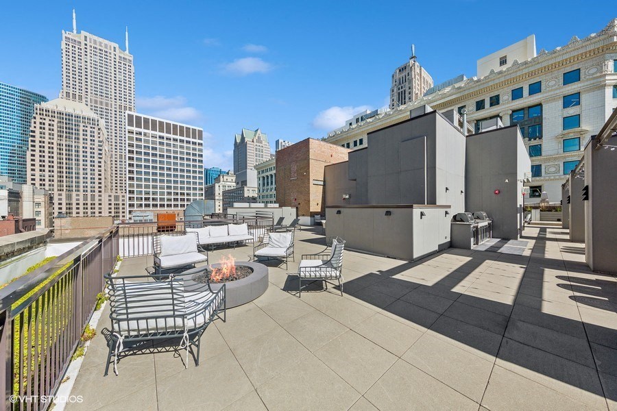 a rooftop patio with a fire pit and chairs on a roof