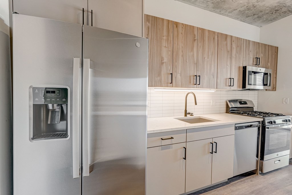 A modern kitchen with a stainless steel refrigerator and white countertops.