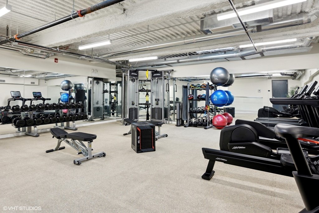 A gym with a variety of equipment including a rowing machine, weight bench, and dumbbells.