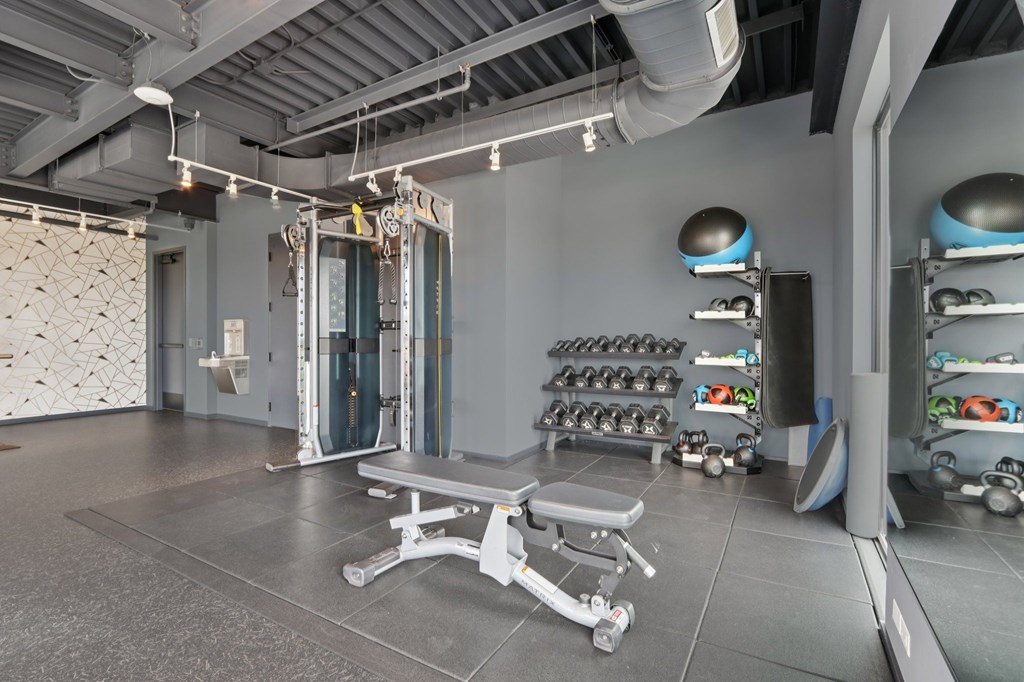 A gym with a bench, weights, and mirrors.