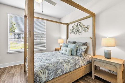 A bedroom with a four poster bed and a wooden nightstand.