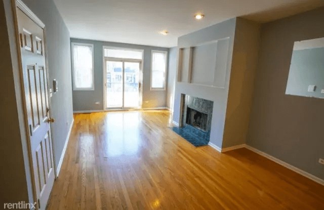 an empty living room with a fireplace and wooden floors