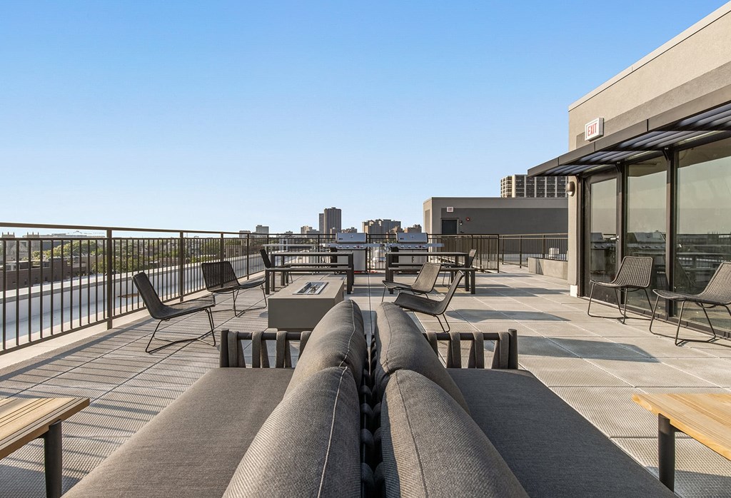 a rooftop patio with tables and chairs and a view of the city