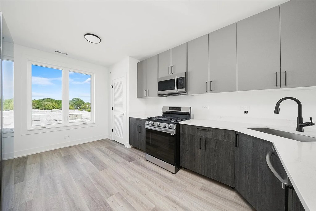A modern kitchen with a white countertop and dark wood cabinets.