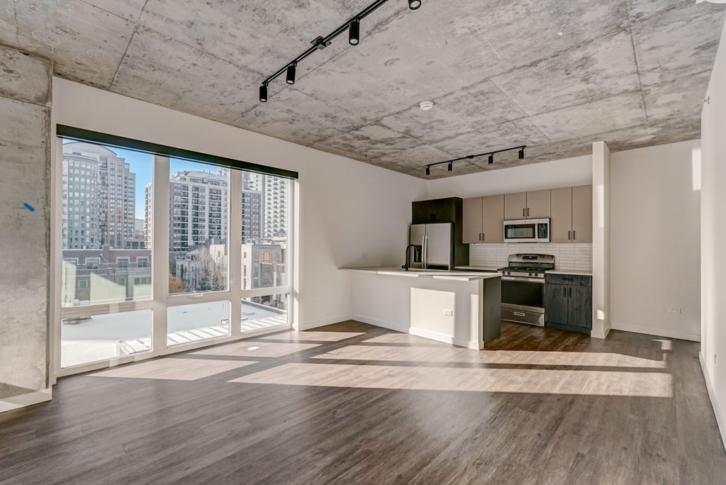 A spacious room with a kitchen area and a view of the city through the windows.