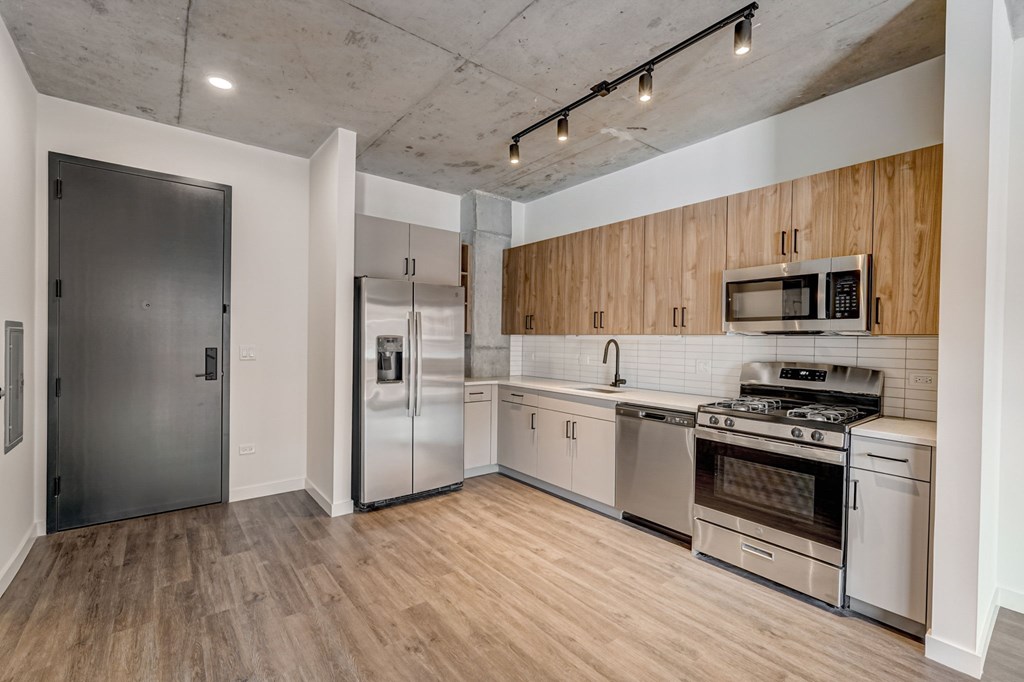 A kitchen with a refrigerator, oven, and microwave.