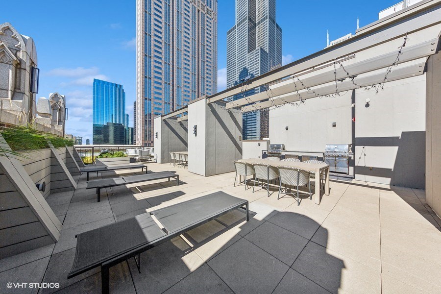 a rooftop patio with tables and chairs and skyscrapers in the background