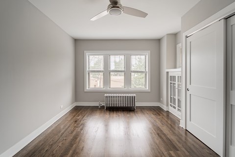 A room with a ceiling fan and a window with blinds.