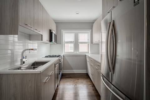 A modern kitchen with a refrigerator on the right and a sink on the left.