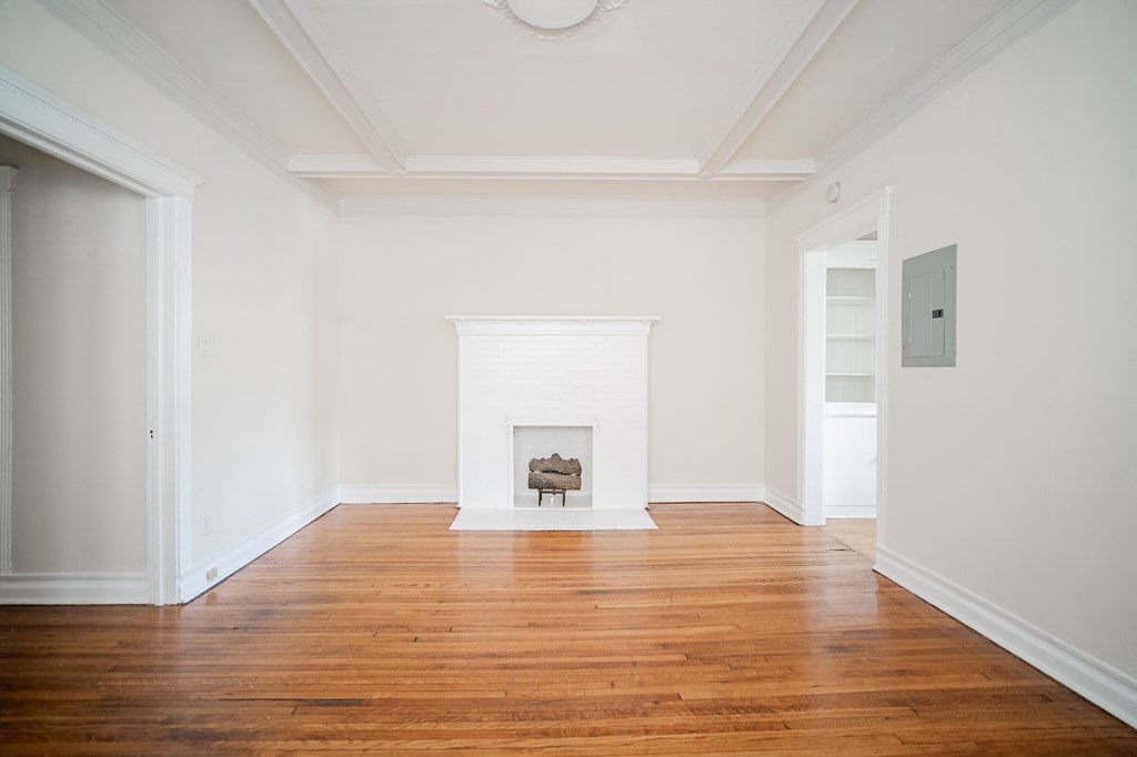 a living room with white walls and a fireplace and wooden floors