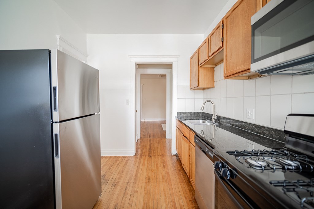 an empty kitchen with stainless steel appliances and wooden cabinets