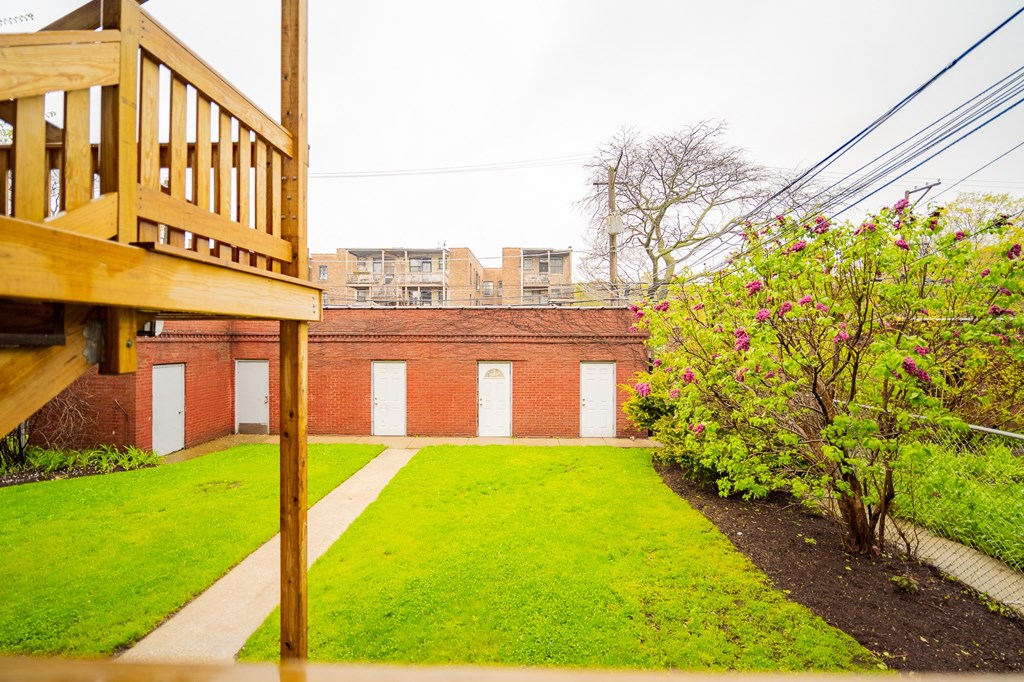 a view of the yard of a brick building with a wooden deck