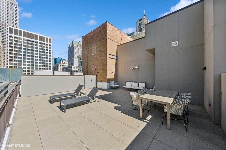 a rooftop patio with a table and chairs and a view of the city