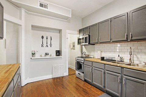 A kitchen with a white wall and a wooden counter top.