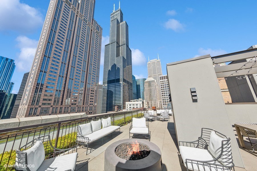 a rooftop patio with a fire pit and a city in the background