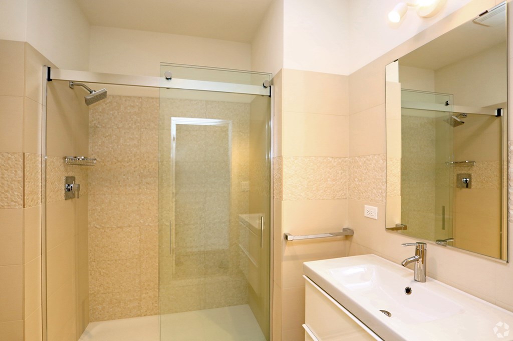 A bathroom with a sink, mirror, and shower.