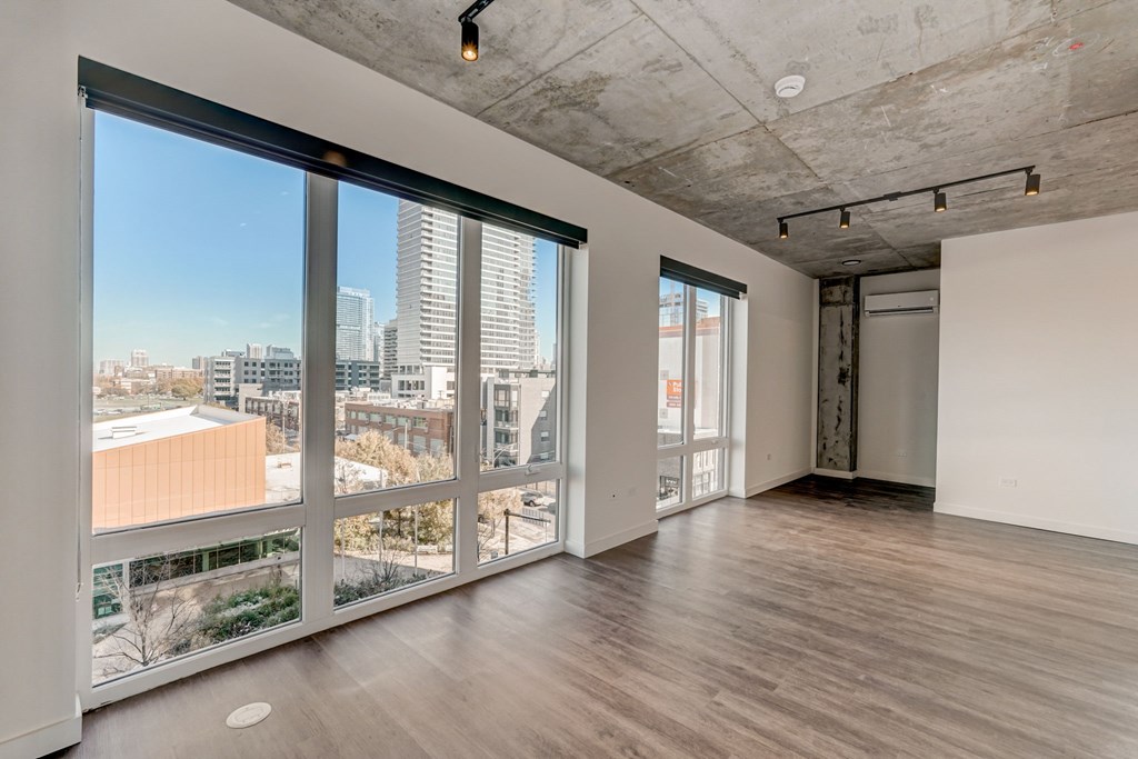 A large empty room with a view of the city outside the windows.