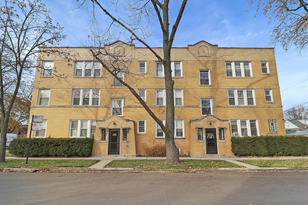 a yellow brick building with a tree in front of it